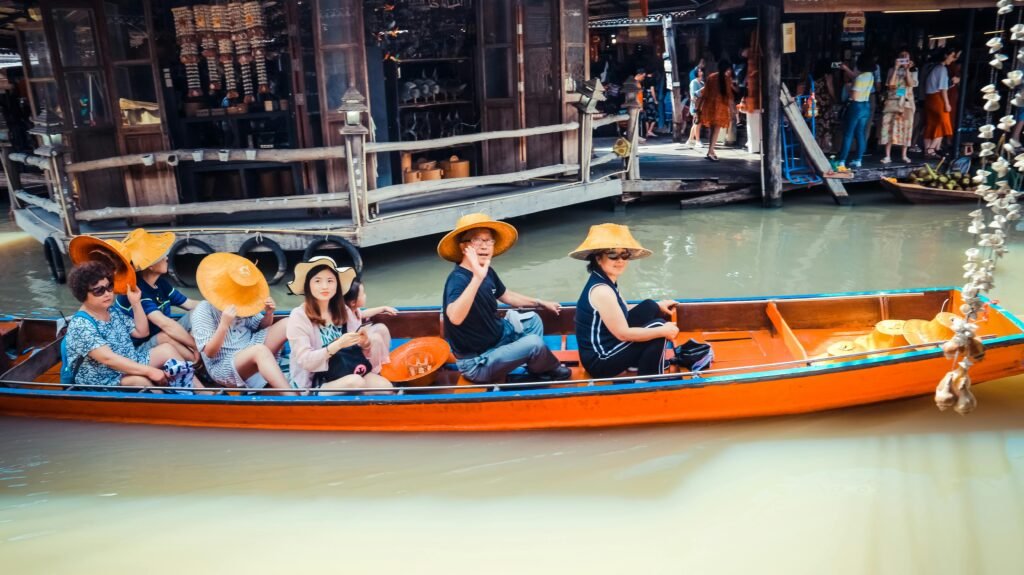 A group of tourists in a boat at a vibrant floating market in Thailand, exploring local culture.