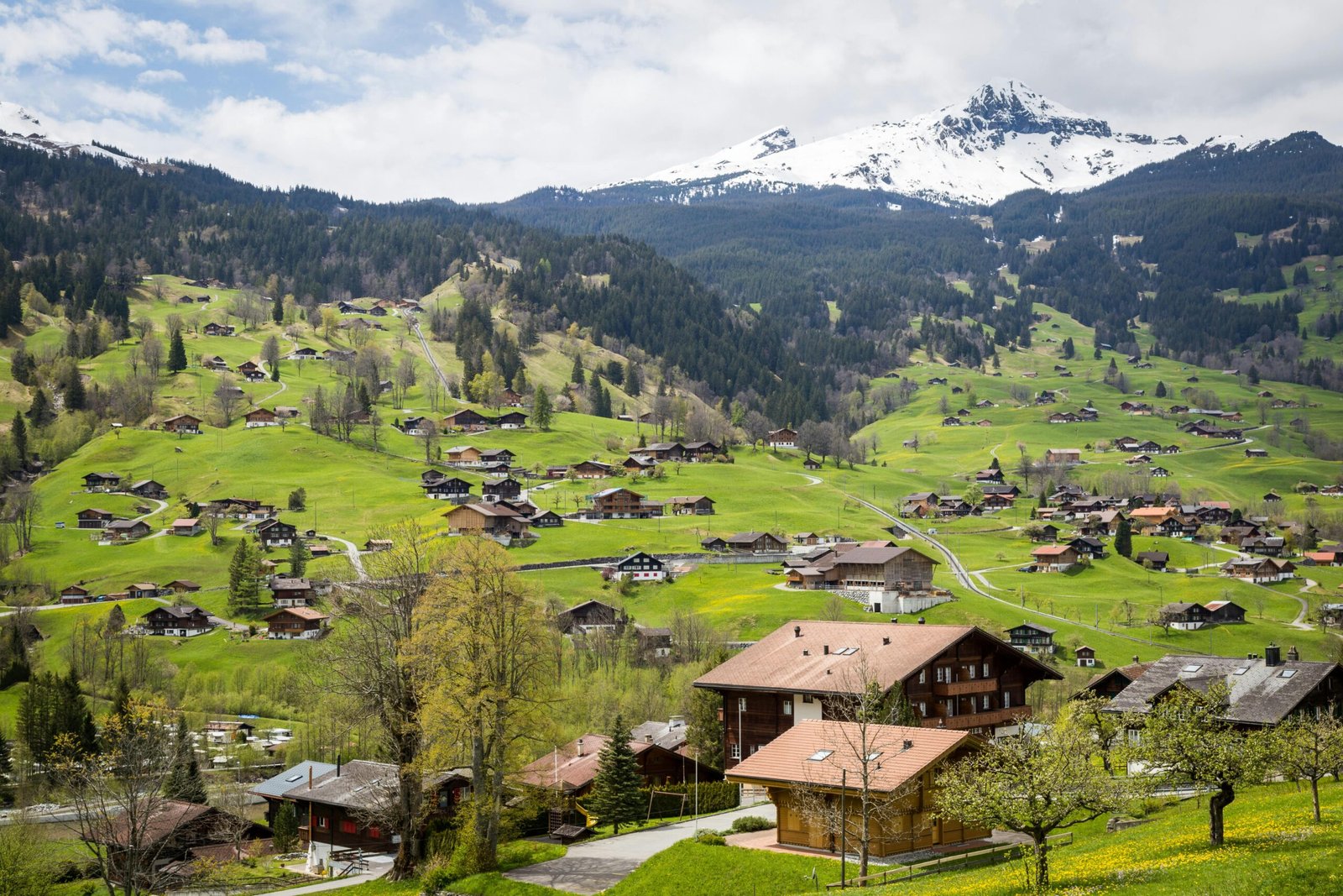 Charming village surrounded by lush green hills and snowy mountains in Interlaken, Switzerland.